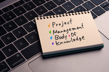 There is notebook with the word Project Management Body of Knowledge. It is as an eye-catching image.
