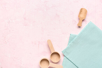 Wooden kitchen utensils and clean napkin on color background