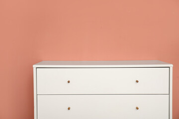 Stylish white chest of drawers near color wall, closeup