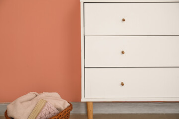 Fototapeta premium Stylish chest of drawers and basket with plaid near color wall, closeup