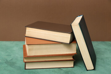 Stack of books on green table against brown background