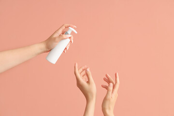 Female hands with bottle of sunscreen cream on color background