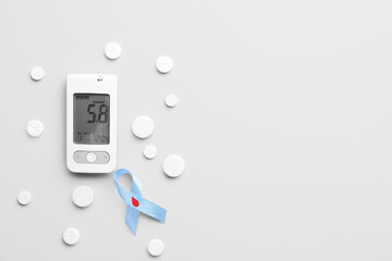 Glucometer with pills and awareness ribbon on light background. Diabetes concept