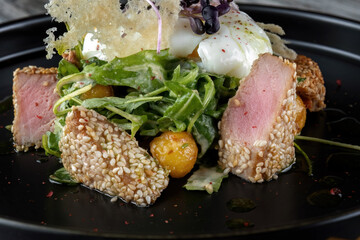 Grilled tuna steak with poached eggs and spinach. Dipped in sesame seeds.