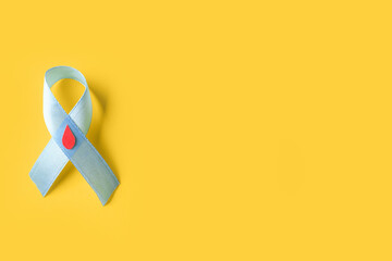 Awareness ribbon with blood drop on yellow background. Diabetes concept