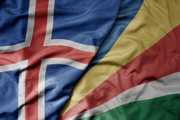 big waving national colorful flag of icelandic and national flag of seychelles .