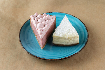 A slice of coconut cheesecake and a slice of cherry cheesecake on a blue plate.