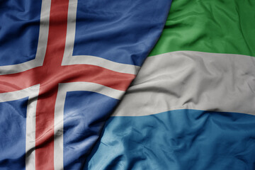 big waving national colorful flag of icelandic and national flag of sierra leone .