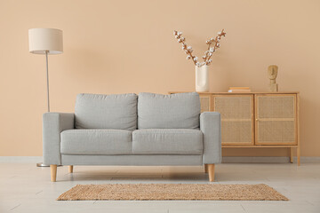 Interior of living room with grey sofa, standard lamp and sideboard