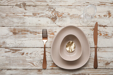 Elegant table setting with golden leaf and cutlery on white wooden background