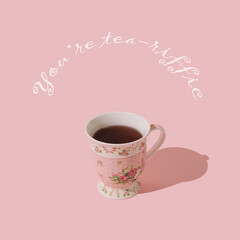Fancy composition made of pink cup of tea on pastel pink background with "You're tea-riffic" message. Minimal creative cup of tea concept. Trendy hot drink idea. Tea aesthetic.