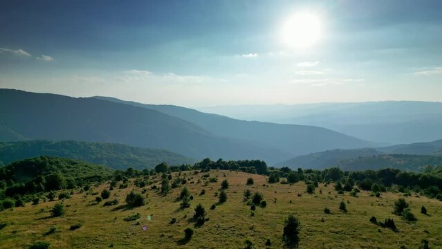 Picturesque nature, beautiful hilly landscape, mountains range ang gleaming sun in a blue sky, aerial