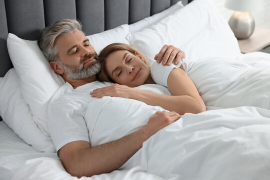 Lovely mature couple sleeping together in bed at home