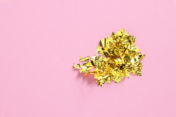 Many pieces of edible gold leaf on pink background, top view. Space for text