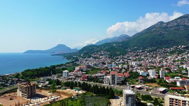 Beautiful city Bar locating on the slopes of green mountains in Montenegro. Sunny urban landscape at the backdrop of stunning nature. Aerial perspective.