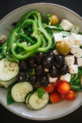Top view of fresh salad with green bell pepper, cherry tomato, cucumber, cheese, olive and rocket.