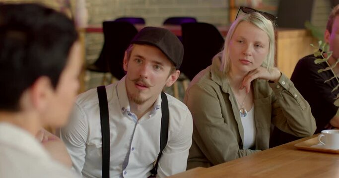 Young man listening attentively to speaker during group discussion. Open mouth reflects emotion of keen interest, enthusiasm for ongoing conversation. Open mouth suggests genuine spontaneous reaction