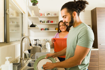 Boyfriend and girlfriend washing the dishes doing house chores together