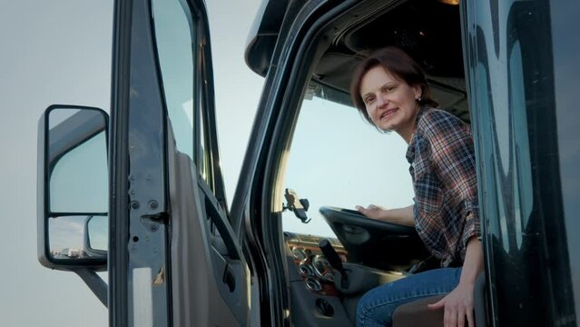 A professional woman trucker stands in a semi truck. Close up shot footage