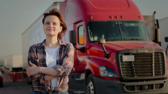 A woman trucker stands in front of a red semi truck