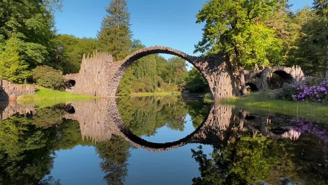 Devil's Bridge Rakotzbrucke in the Rhododendron Palace Landscape Park Kromlau, Lake Rakotz, Saxony, Germany. High quality 4k footage