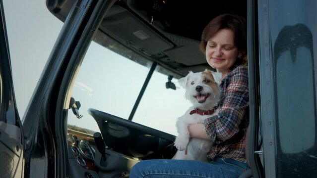 A woman trucker sit in a semi truck along with the dog. Close up shot