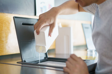 Asian middle adult man pouring a washing detergent and liquid softening solution in the automatic washing machine detergent tray. Man washing his clothes at self-service or automatic washing machine.