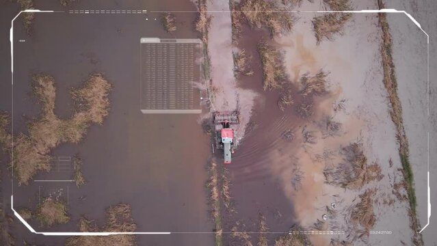 Scenic landscape drone shot the tractor is is shoveling a ground of rice field farm With Ai Tracker , HUD Head-up display. Technology and futuristic concept