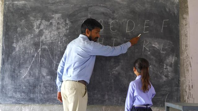 Indian Rural elementary school teacher teaching kids some lesson in the class with excitement and joy.