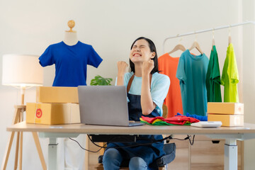 Successful Asian woman entrepreneur raising hands with surprise smiling happily on laptop at home. Small business owner Asian woman who are delighted with successful at home.