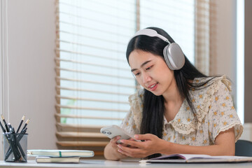 Cheerful Asian woman wearing headphone and use smart phone.