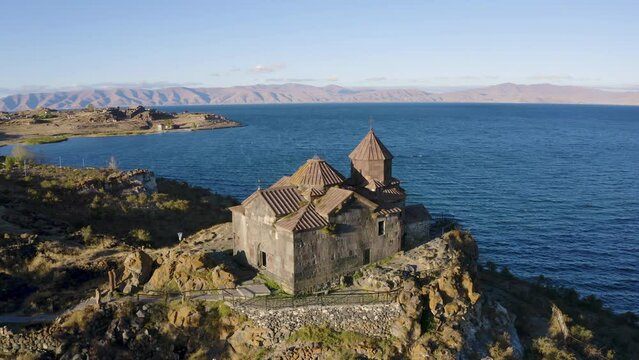 Forward reveal aerial shot of Hayravank Monastery and Sevan Lake on sunny summer evening. Gegharkunik Province, Armenia.
