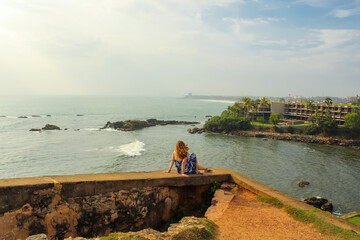 The girl sitting on the walls of the ancient fortress overlooking the bay