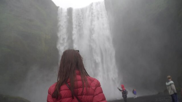 The girl goes to a big waterfall. Iceland.
