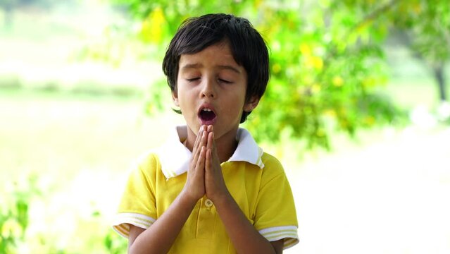 Portrait of Happy Indian Boy Praying and worship to God in School. Hand praying and palm up, Concept Praise and worship with faith spirituality and Surrender