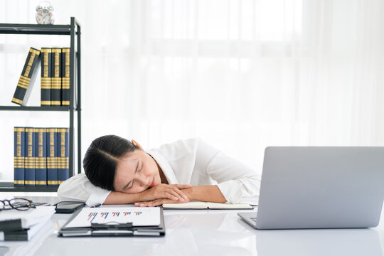 Overworked and tired businesswoman sleeping over a laptop in a desk at work in her office