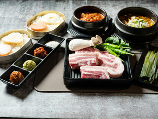 A set of various parts of raw pork, side dishes, and stew
