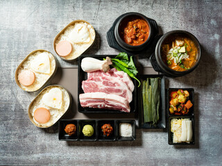 A set of various parts of raw pork, side dishes, and stew