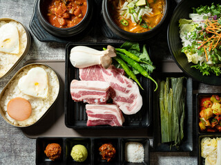 A set of various parts of raw pork, side dishes, and stew