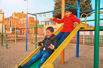 two very happy latin brother and sister children smiling playing on the slide of an outdoor park in la paz bolivia, latin america