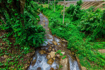 Obraz premium Background of a natural waterfall with cool water flowing from high mountains, Punyaban Waterfall Lamnam Kraburi National Park in Ranong Province, Thailand