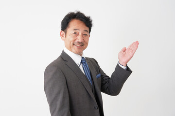 手の平で右側を指す中年のビジネスマン　白背景