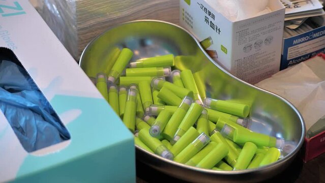 Slow motion shot of a silver kidney dish full of blood glucose monitoring needles