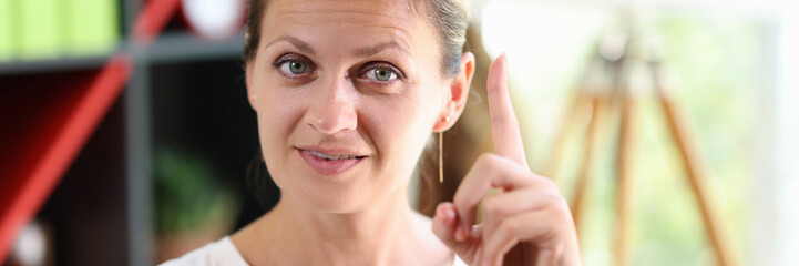 Female shows gesture with her index finger up.