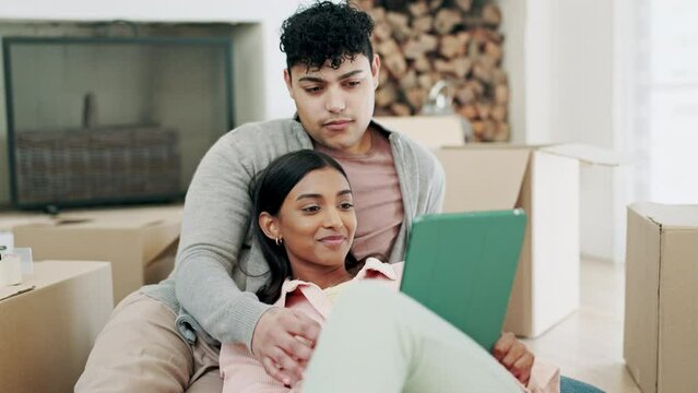 Couple, tablet and boxes for new home planning, social media and website information of mortgage, rent or loan. Young interracial people, relax on floor and digital, moving house or real estate idea