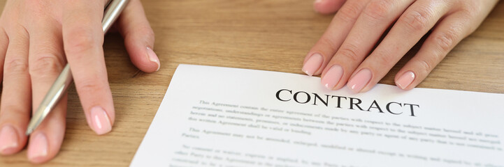Female manager asks to sign contract while sitting at desk in office.