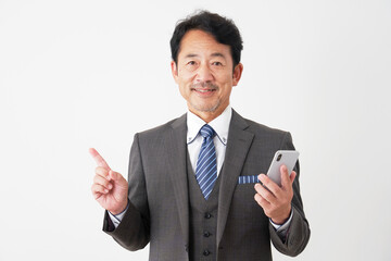 スマホを持って左側を指差す中年のビジネスマン　白背景