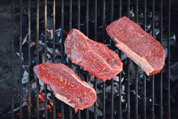 Top view of beef steaks on grid of grill