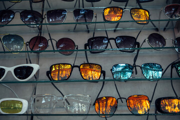 Lots of sunglasses on the glass display case. Unusual background with beautiful reflections of blue...