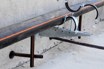 Black plastic pipe in the process of installation before soldering underfloor heating pipes, on a...